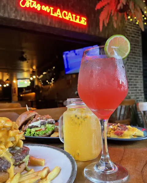 Cóctel rojo, limonada y hamburguesas bajo el letrero de neón de La Calle