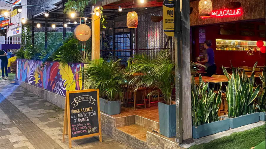 Terraza de La Calle Burger 33 con plantas, mural de colores y luces